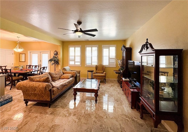 living area with marble finish floor, ceiling fan, and baseboards