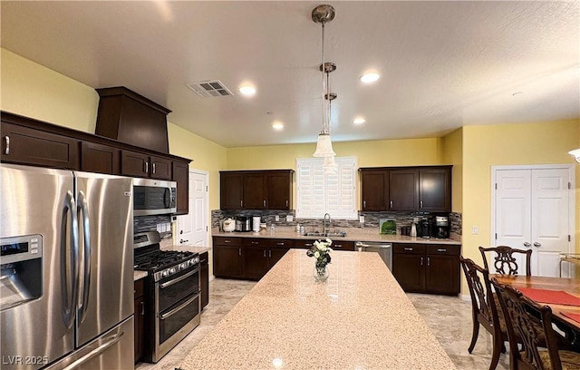 kitchen featuring decorative backsplash, a sink, appliances with stainless steel finishes, visible vents, and dark brown cabinetry