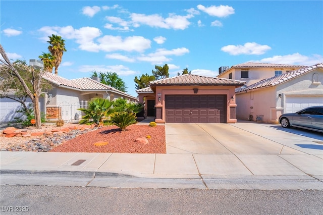 mediterranean / spanish-style house featuring a garage, stucco siding, a tile roof, and concrete driveway