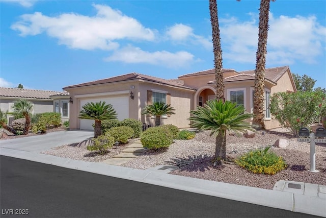 mediterranean / spanish home with a garage, a tile roof, stucco siding, and driveway