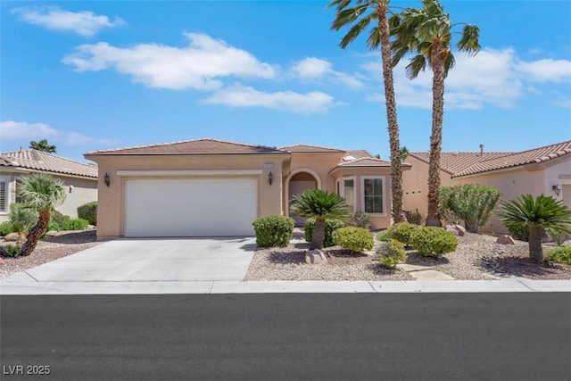 mediterranean / spanish home with stucco siding, a tile roof, concrete driveway, and an attached garage