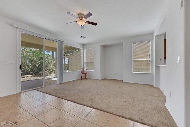 empty room with light tile patterned flooring, ceiling fan, light carpet, and baseboards