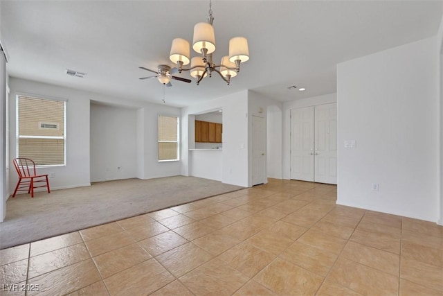 empty room featuring recessed lighting, ceiling fan with notable chandelier, light carpet, visible vents, and light tile patterned flooring