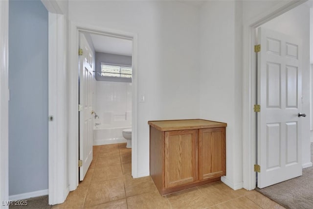 hall with baseboards and light tile patterned floors