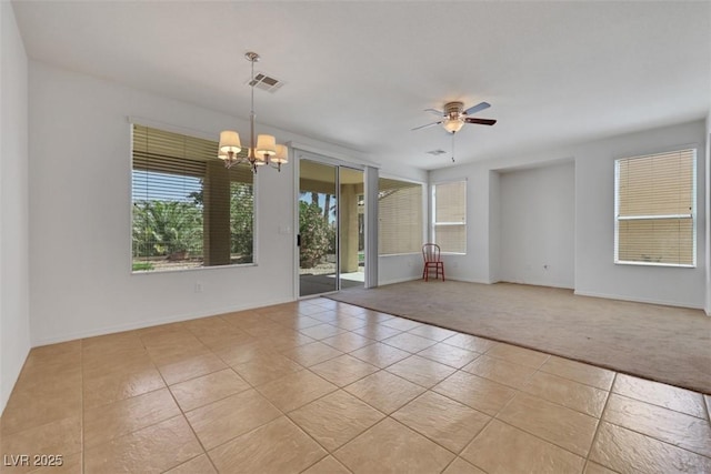 spare room featuring light tile patterned floors, visible vents, baseboards, light colored carpet, and ceiling fan with notable chandelier