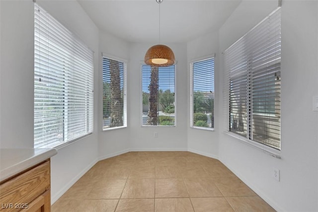 unfurnished dining area featuring baseboards and light tile patterned floors