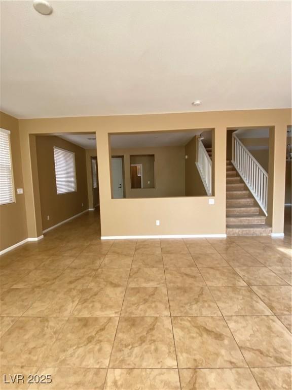 10349 Mystic Pine Rd, Las Vegas, NV 89135 - unfurnished living room with stairway, light tile patterned flooring, and baseboards
