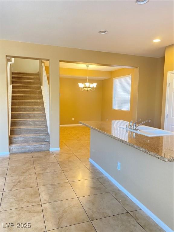 10349 Mystic Pine Rd, Las Vegas, NV 89135 - kitchen with light tile patterned floors, light stone countertops, a chandelier, baseboards, and pendant lighting