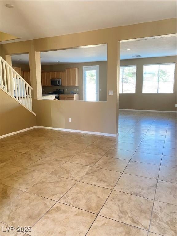 10349 Mystic Pine Rd, Las Vegas, NV 89135 - unfurnished living room featuring light tile patterned floors, baseboards, and stairs
