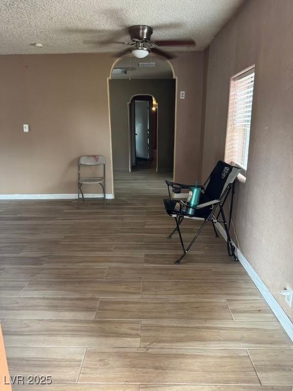 4834 E Van Buren Ave, Las Vegas, NV 89110 - unfurnished room featuring light wood finished floors, a textured ceiling, ceiling fan, baseboards, and arched walkways