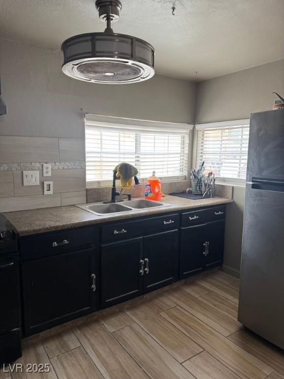 4834 E Van Buren Ave, Las Vegas, NV 89110 - kitchen featuring freestanding refrigerator, a sink, black gas range oven, wood finish floors, and dark cabinetry