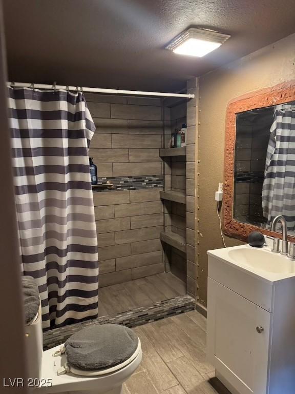 4834 E Van Buren Ave, Las Vegas, NV 89110 - full bathroom featuring a textured ceiling, a tile shower, vanity, toilet, and wood finish floors