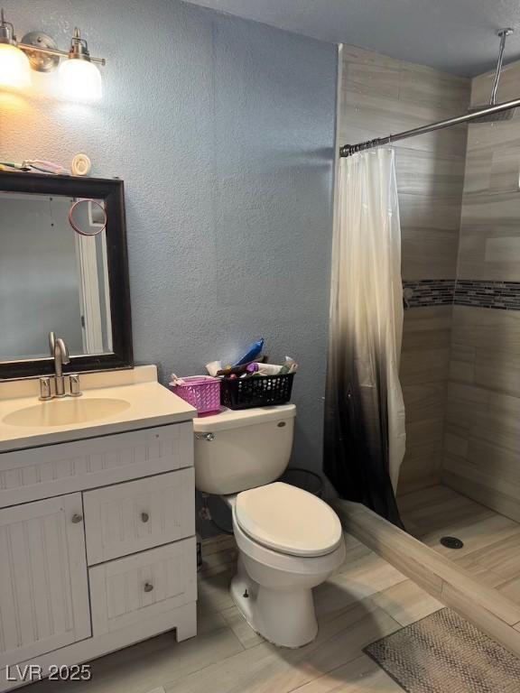 4834 E Van Buren Ave, Las Vegas, NV 89110 - bathroom with toilet, vanity, tiled shower, and a textured wall
