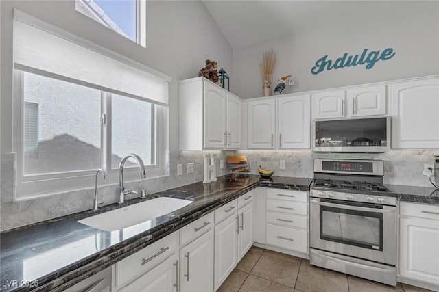 5205 Molveno Ct, Las Vegas, NV 89130 - kitchen with stainless steel appliances, lofted ceiling, tasteful backsplash, white cabinetry, and light tile patterned floors