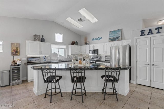 5205 Molveno Ct, Las Vegas, NV 89130 - kitchen with wine cooler, white cabinetry, high vaulted ceiling, light tile patterned floors, and a breakfast bar