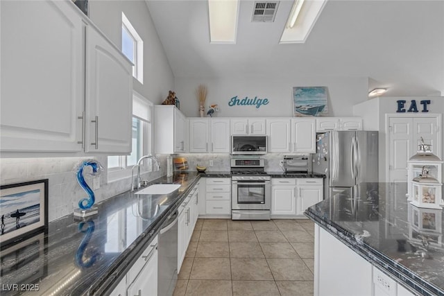5205 Molveno Ct, Las Vegas, NV 89130 - kitchen with stainless steel appliances, white cabinetry, decorative backsplash, light tile patterned flooring, and high vaulted ceiling