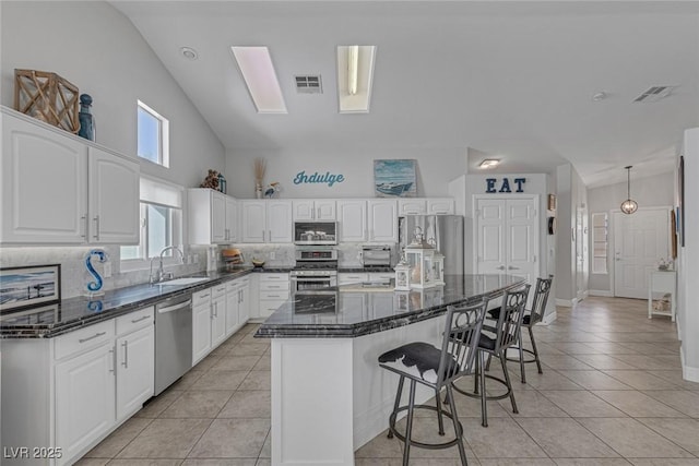 5205 Molveno Ct, Las Vegas, NV 89130 - kitchen featuring stainless steel appliances, a kitchen breakfast bar, decorative backsplash, a center island, and high vaulted ceiling