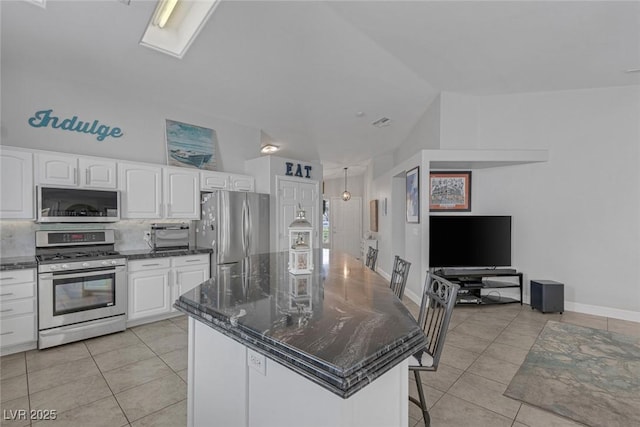 5205 Molveno Ct, Las Vegas, NV 89130 - kitchen with stainless steel appliances, light tile patterned flooring, white cabinets, a breakfast bar, and vaulted ceiling