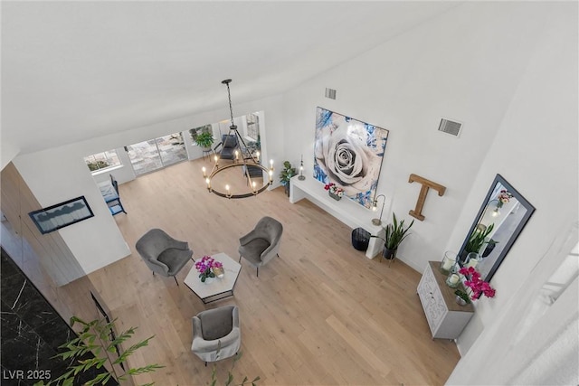 unfurnished living room featuring an inviting chandelier, visible vents, high vaulted ceiling, and wood finished floors