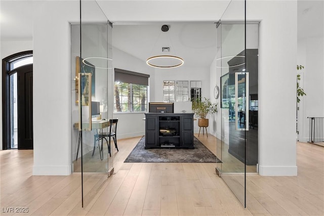interior space with baseboards, high vaulted ceiling, wood finished floors, and visible vents