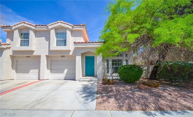 mediterranean / spanish house featuring stucco siding, a tile roof, concrete driveway, and an attached garage
