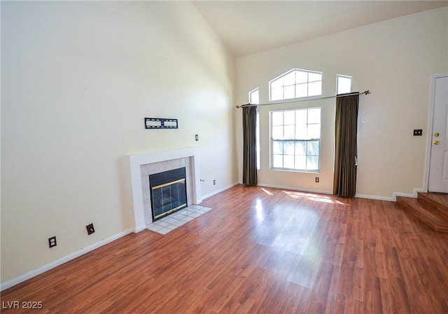 1000 Grammy Dr, Las Vegas, NV 89145 - unfurnished living room with high vaulted ceiling, wood finished floors, a tiled fireplace, and baseboards