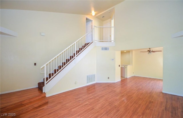 1000 Grammy Dr, Las Vegas, NV 89145 - unfurnished living room with stairs, ceiling fan, wood finished floors, a towering ceiling, and baseboards