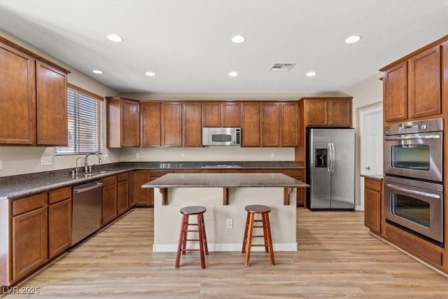 8140 Redbud Vine St, North Las Vegas, NV 89085 - kitchen with light wood-type flooring, a kitchen island, appliances with stainless steel finishes, and a kitchen bar