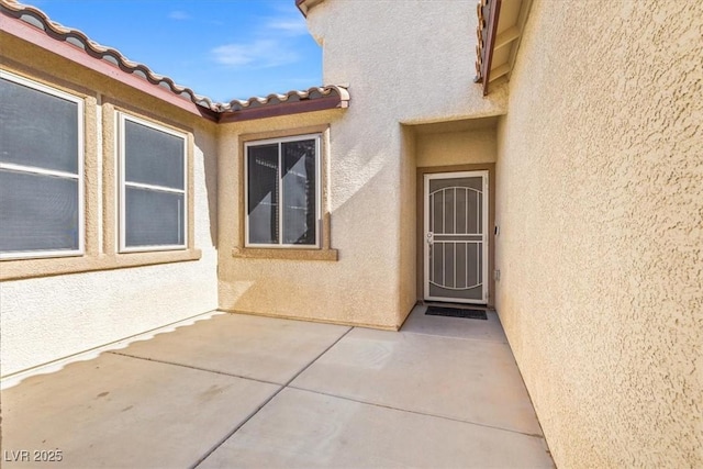 8140 Redbud Vine St, North Las Vegas, NV 89085 - view of exterior entry featuring stucco siding, a tiled roof, and a patio area