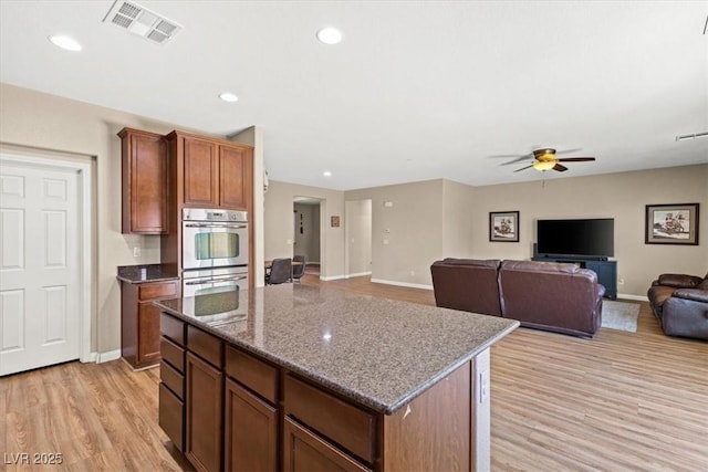 8140 Redbud Vine St, North Las Vegas, NV 89085 - kitchen featuring stainless steel double oven, light wood-style flooring, a center island, visible vents, and a ceiling fan
