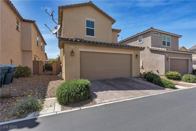 view of front of home with a tile roof, driveway, a gate, and stucco siding