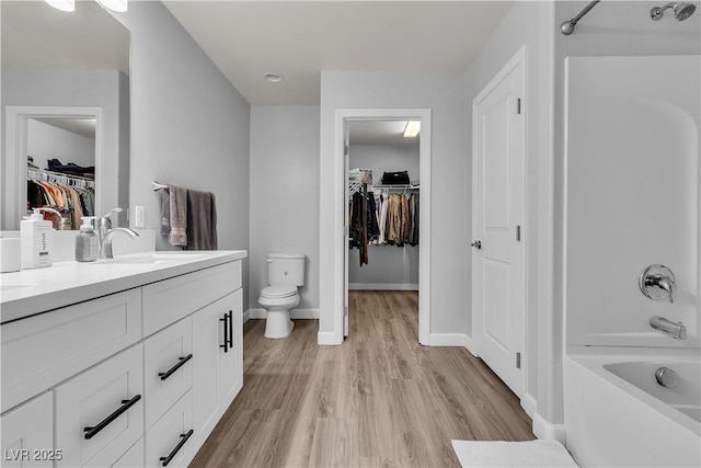 bathroom featuring bathtub / shower combination, vanity, toilet, baseboards, and wood finished floors
