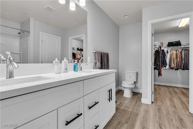 bathroom featuring a sink, toilet, wood finished floors, and visible vents