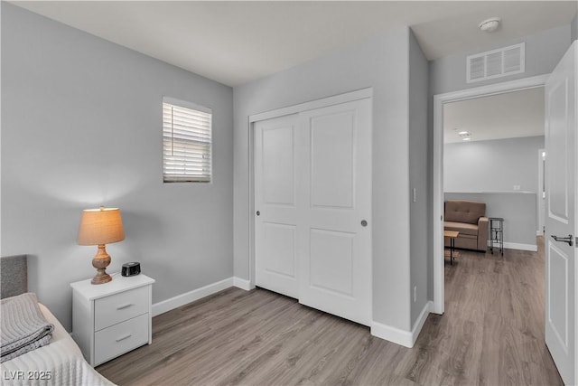 bedroom featuring baseboards, visible vents, wood finished floors, and a closet