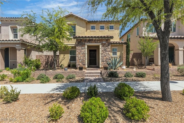 mediterranean / spanish house featuring stucco siding, stone siding, and a tile roof
