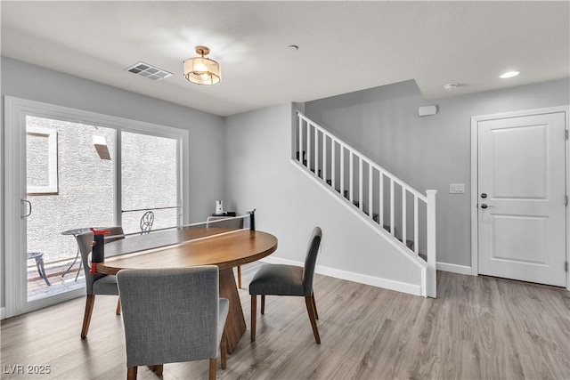 dining area featuring visible vents, light wood-style flooring, stairs, and baseboards