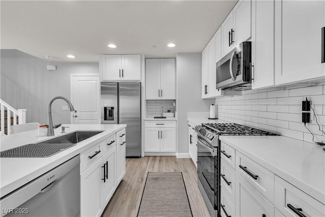 kitchen featuring light countertops, stainless steel appliances, white cabinetry, and a sink