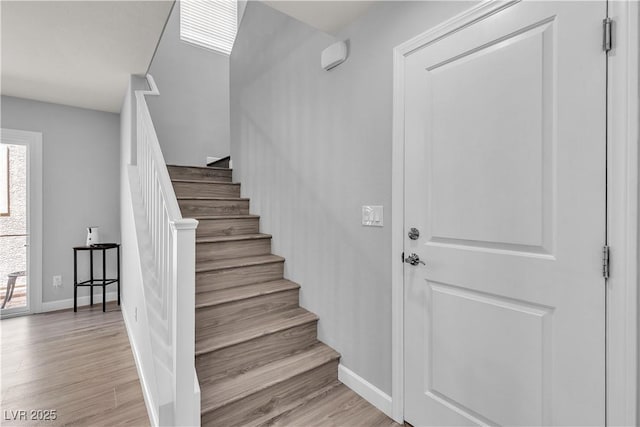 stairs featuring baseboards, a healthy amount of sunlight, and wood finished floors