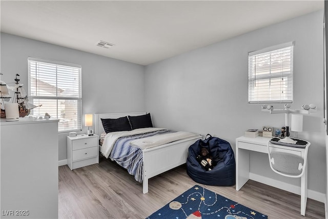 bedroom featuring baseboards, wood finished floors, and visible vents