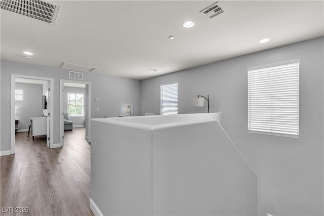 hallway with recessed lighting, wood finished floors, and visible vents
