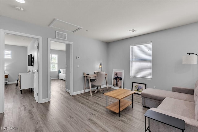 living room featuring visible vents, attic access, baseboards, and wood finished floors