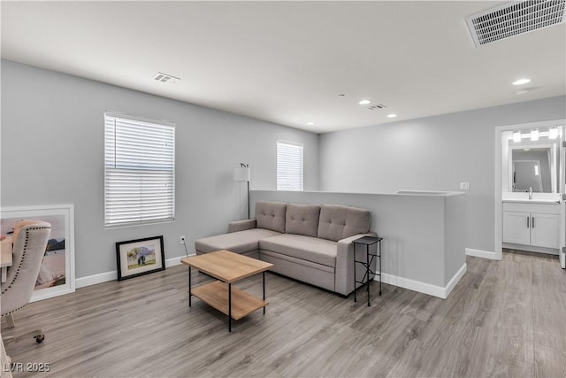 living room featuring baseboards, visible vents, and light wood-style floors