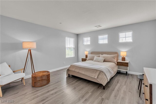 bedroom featuring baseboards, multiple windows, light wood finished floors, and visible vents