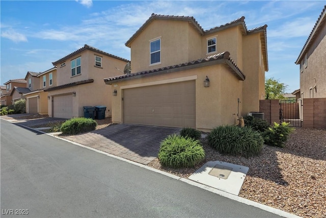 view of front of house with an attached garage, a gate, stucco siding, and a tiled roof
