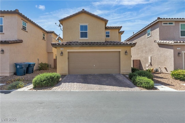 view of front of home featuring an attached garage, stucco siding, a tiled roof, and driveway