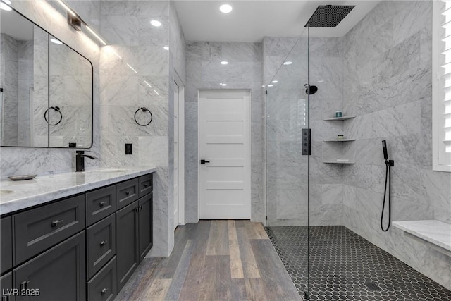 bathroom with vanity, a walk in shower, wood finished floors, and tile walls