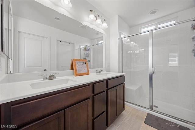 bathroom with double vanity, a sink, and a stall shower