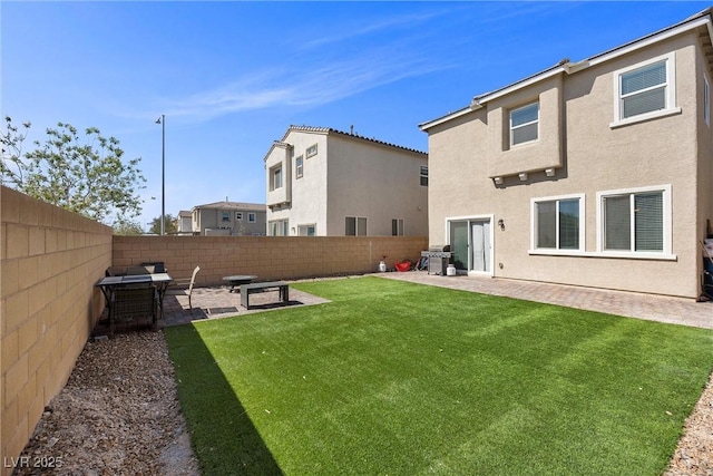 rear view of house featuring a lawn, a fenced backyard, a patio area, and stucco siding