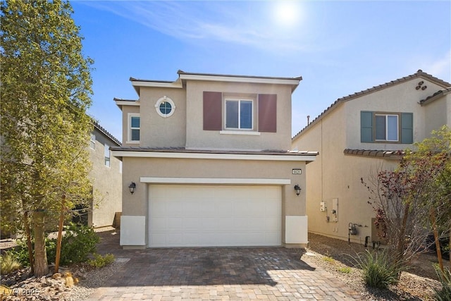 traditional-style house featuring decorative driveway, a garage, and stucco siding
