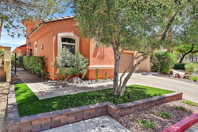 view of front of home with stucco siding, a gate, fence, a garage, and driveway